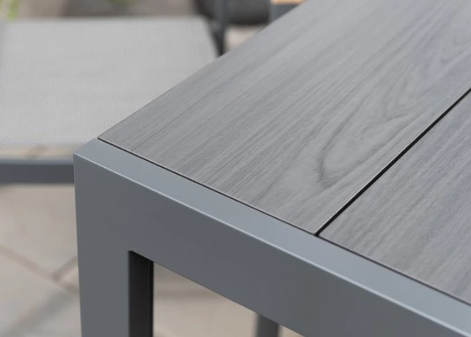 Närbild av BORD ESSENCE ALU 156 bord, grå metall med trästrukturerad yta och stol.