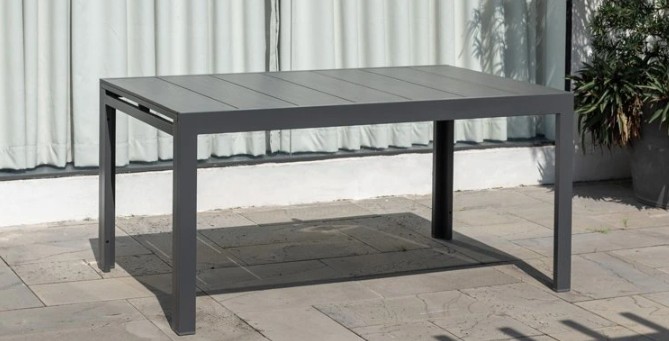 Bordet BORD ESSENCE ALU 156 - 246 x 95 cm i grå metall står på en uteplats i sten.