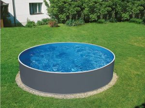 En AZURO GRAPHITE-pool med måtten 4,60 m i diameter och 1,20 m djup står på en gräsmatta nära ett hus och några buskar.